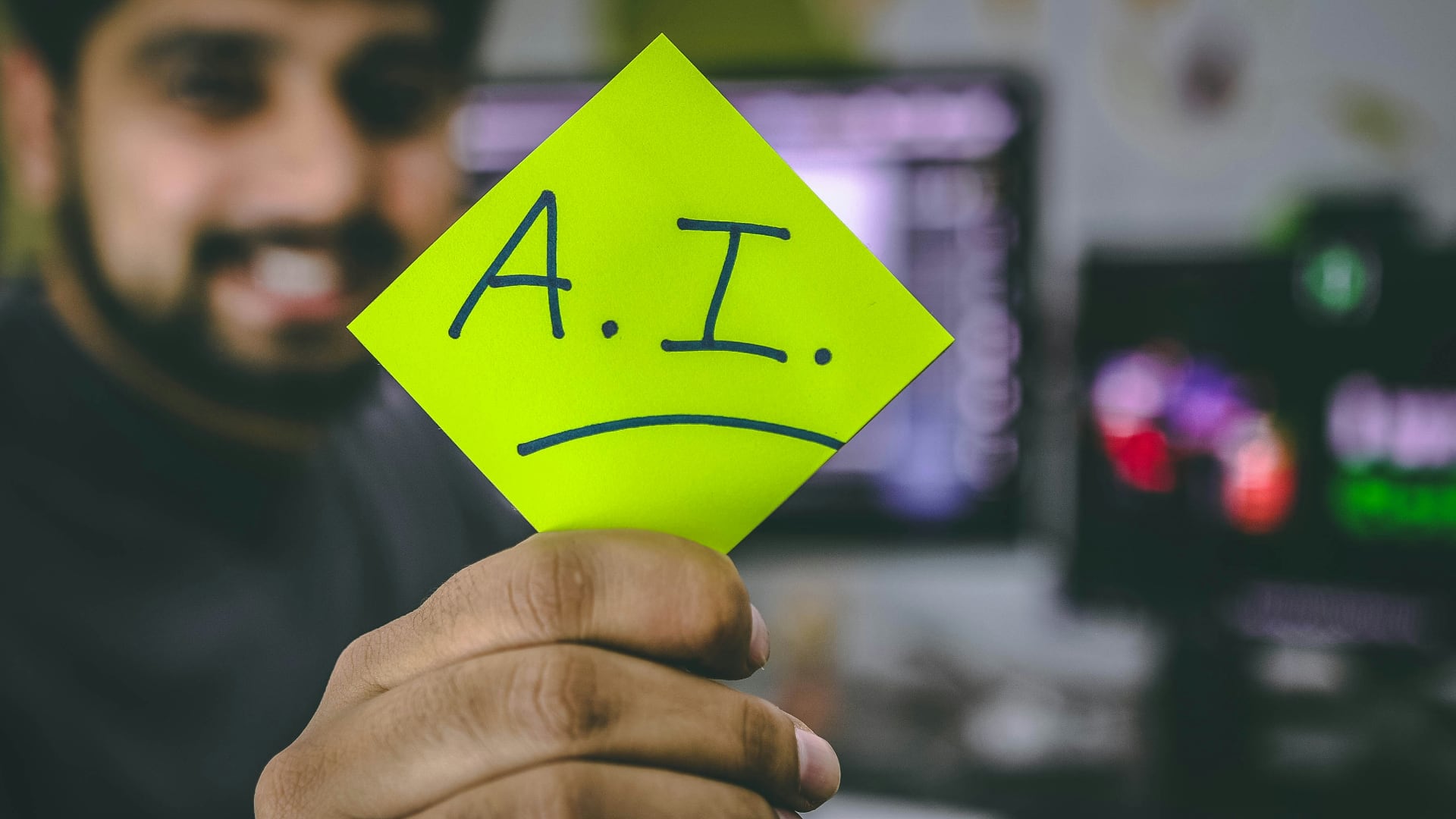 A man holding a yellow Post-It note with the word AI written on it